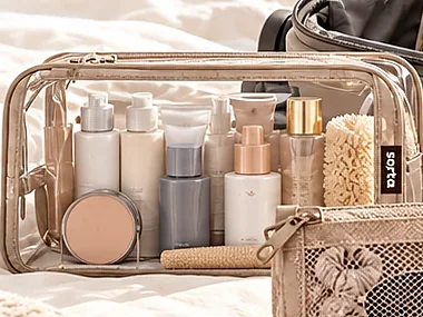 A clear toiletry pouch filled with bottles and skincare.